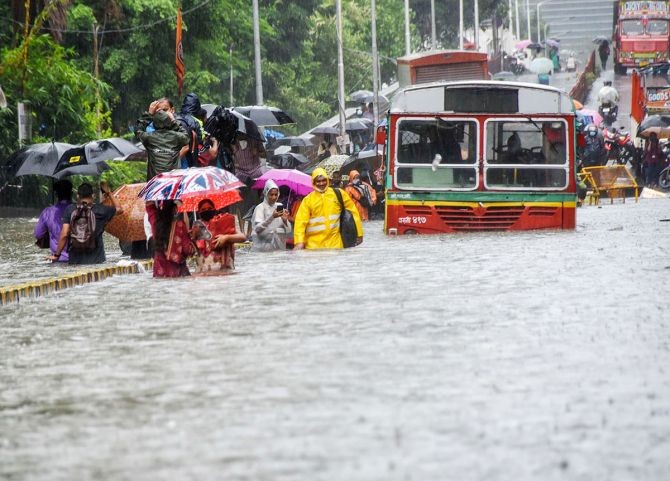 Commuters wade through a waterlogged street at Parel following heavy rainfall in Mumbai. Photograph: PTI Photo